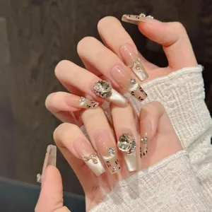 Detail of handmade coffin nails with leopard patterns, gold chains, and 3D rhinestones