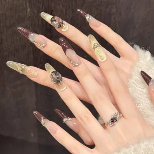 Détail d'ongles amande longs avec effet œil de chat marron et strass de luxe brillants