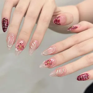 Dettaglio di unghie a mandorla rosa e rosso scuro con decorazioni floreali 3D e oro lucido