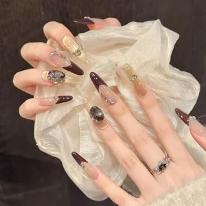 Gros plan d'ongles caramel œil de chat ornés de gemmes et perles sur une main