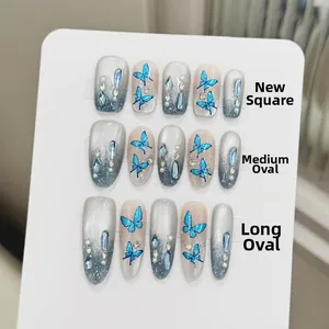 Detail of blue butterfly gradient press-on nails with rhinestones and pearls on display