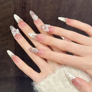 Detail of handmade cream bow press-on nails with 3D pearls and crystals on hand