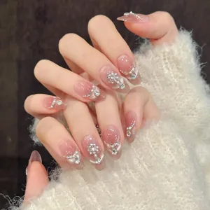 Detail of peach pink almond press-on nails with silver glitter, snowflakes and rhinestones