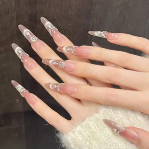 Macro shot of long almond peach cat-eye press-on nails with luxury rhinestones and pearls