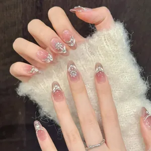 Macro detail of almond-shaped press-on nails with peach gradient and pearl diamond accents