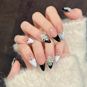 Detail of almond-shaped press-on nails with 3D white flowers and black French tips