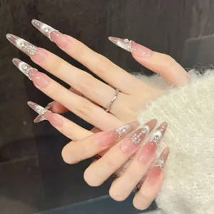 Detail of almond press-on nails with peach cat eye gloss and 3D floral rhinestones