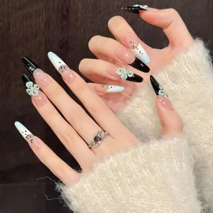 Macro shot of press-on nails featuring black French tips and green 3D flower accents