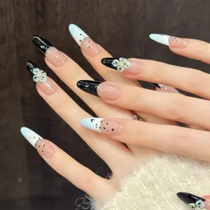 Macro view of long almond press-on nails with 3D white flowers and black French tips