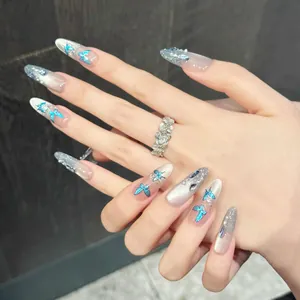 Handmade almond press-on nails featuring blue butterflies and shimmering blue rhinestones