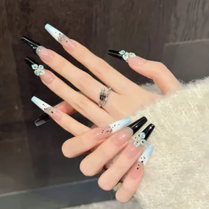 Coffin press-on nails with black splatter design and 3D floral accents on hand