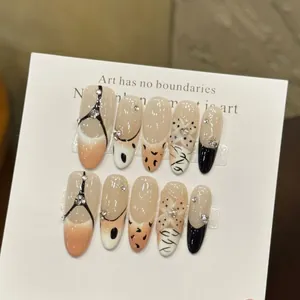 Detail of almond-shaped press-on nails with hand-painted leopard prints and crystal accents