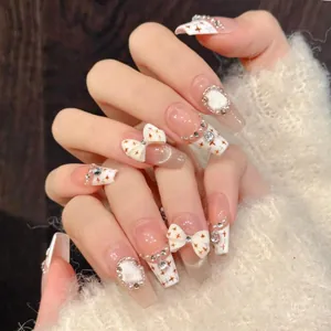 Macro detail of French style press-on nails with bow, pearls and rhinestones on long coffin shape
