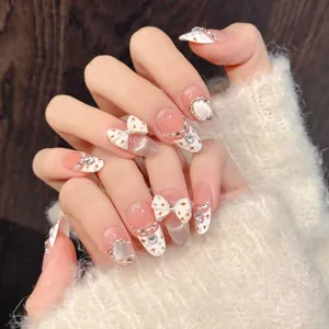 Detailed close-up of handmade press-on nails with 3D bows, pearls and cat-eye glitter