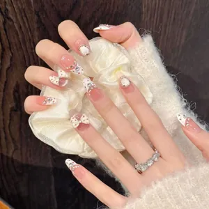 Close-up of French press-on nails with white bows, pearls and crystal star details