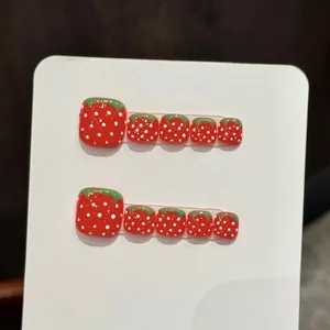 Vue macro de faux ongles de pieds fraise avec finition rouge brillante et pois