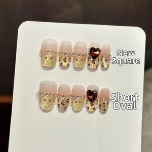 Detailed view of handmade leopard print press-on nails with heart rhinestones and gold glitter
