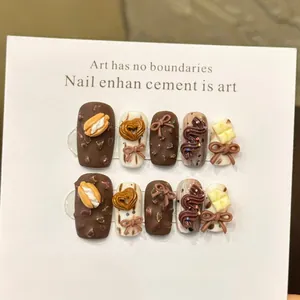 Detail von handgefertigten 3D-Schokoladen-Nägeln mit süßer Schleife und Textur-Details