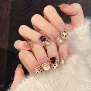 Detail of handmade leopard print press-on nails with golden glitter and heart gemstone