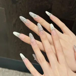 Long almond press-on nails with white 3D flowers, pearls, and crystals in French style