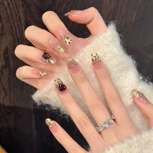 Handmade leopard print press-on nails with golden glitter and heart gemstone accents