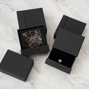 Macro detail of textured black jewelry gift boxes with silver necklace and gemstone ring