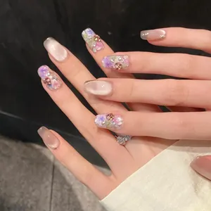Dettaglio di unghie finte fatte a mano effetto cat-eye con fiori 3D e strass di cristallo