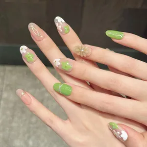 Detail of handmade press-on nails with 3D floral accents, pearls, and green art
