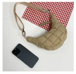 Detailed view of khaki quilted crescent bag with textured surface and phone for scale