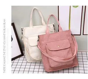 Detail view of corduroy tote bags in beige and pink with a snap front pocket and strap