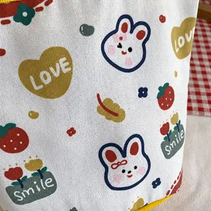 Detail of canvas bucket bag with cute rabbit and strawberry prints on red checkered fabric
