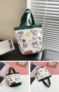 Close-up of cute canvas bucket bag featuring rabbit prints and green top handles