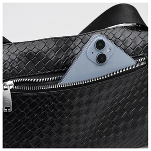 Détail d'un sac tressé noir avec une fermeture éclair argentée et une poche pour téléphone