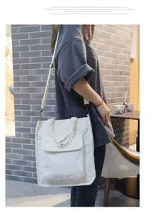 Side view of white corduroy tote bag with adjustable shoulder strap on female model