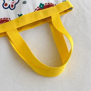 Detail view of durable yellow nylon strap and stitching on canvas bucket bag