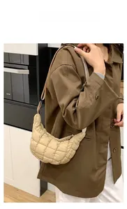 Model showing the beige quilted crescent shoulder bag in a modern kitchen setting