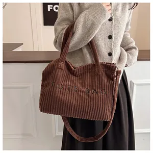 Close-up of brown corduroy tote bag with black letter embroidery and soft texture