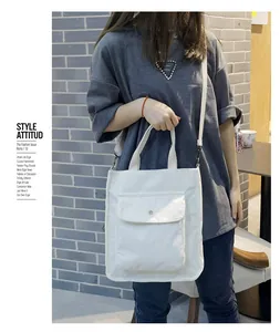 Close-up of a white corduroy tote bag featuring a front flap pocket and texture details
