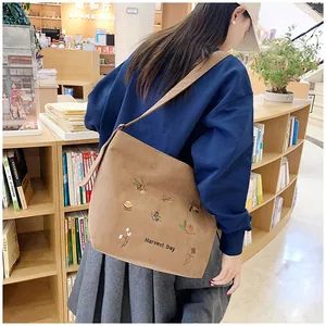 Detail of tan corduroy tote with acorn embroidery on shoulder in bookstore setting