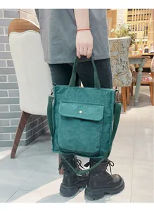 Deep green corduroy tote bag with front pocket and adjustable strap held by a model