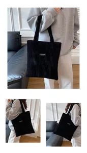Dettaglio della borsa tote nera in velluto a coste con trama a costine e etichetta Fashion