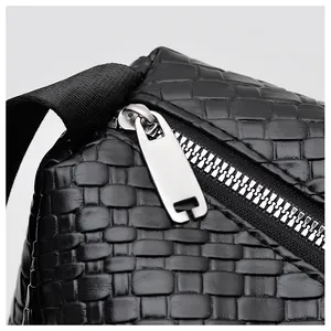 Gros plan sur la texture du cuir tressé noir et les détails du zip en métal argenté