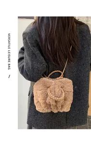 Détail du sac à bandoulière en peluche marron avec poignée tressée sur manteau