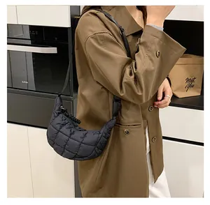 Detail of black quilted croissant bag with puffy texture on a casual trench coat