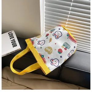 Detail of a small canvas tote bag featuring cute cartoon rabbit prints and yellow handles
