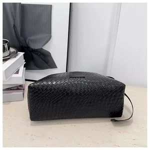Gros plan d'un sac en cuir tressé noir montrant le motif Intrecciato et les détails métalliques