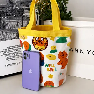 Détail du sac seau en toile tigre jaune montrant la comparaison avec un smartphone