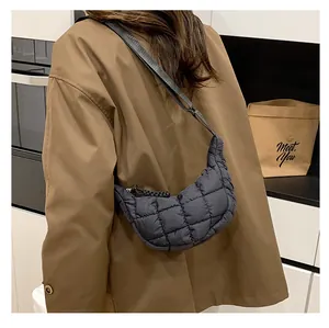 Close-up of black quilted dumpling bag worn by a model in a modern indoor setting