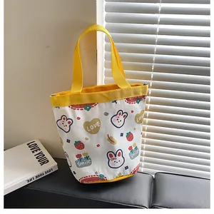 Detail of canvas bucket bag with yellow handles featuring cute cartoon rabbit prints