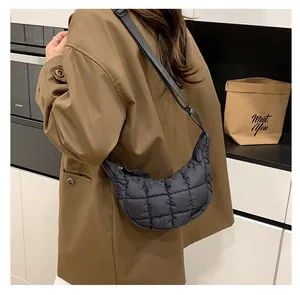 Detail of black quilted dumpling bag with adjustable wide strap and soft textured padding